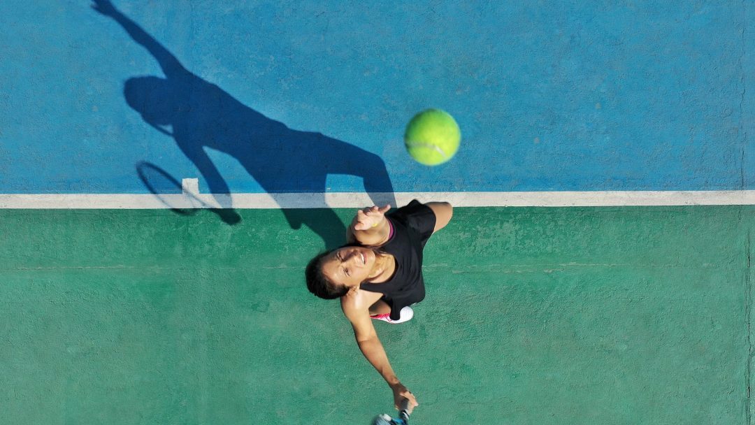 une-jeune-adulte-femme-tennisiste-jette-la-balle-en-l'air-pour-servir-créant-une-ombre-sur-le-court appli-fft